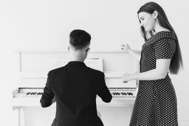 pretty-smiling-young-woman-looking-man-playing-piano